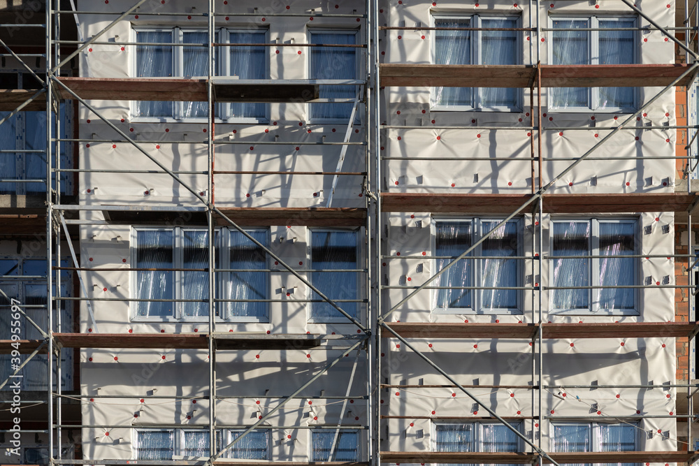 Scaffolding for building insulation and finishing. The process of building a house, working with the facade. Abstract photography of the construction process.