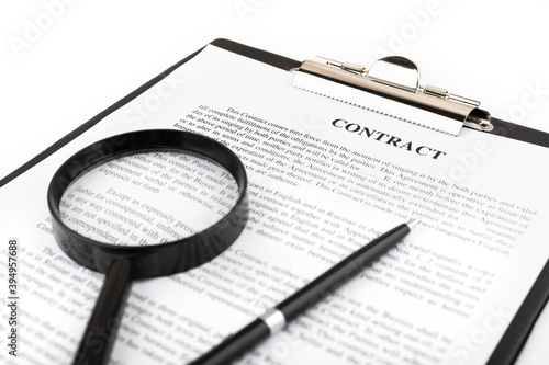 Magnifier and pen lying on a contract or application form on white table. Close up.
