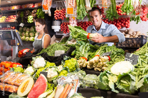 Two nice sellers working behind the counter of vegetable shop photo