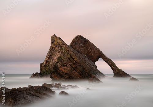 Bow Fiddle rock is located on the beautiful north coast of Scotland. Photo was taken during sunset with very nice soft pastel colors in the sky and with a long shutter speed.