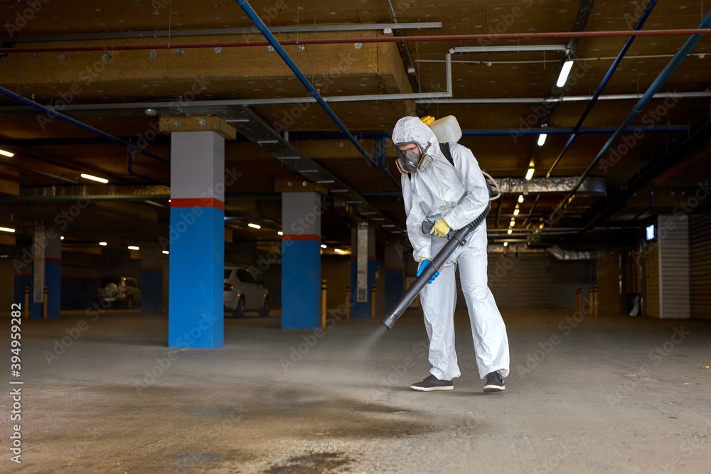 disinfector in hazmat suit working with pressure washer or sanitizer outdoors, wearing medical mask, gloves and goggles disinfector in hazmat suit working with pressure washer or sanitizer outdoors, wearing medical mask, gloves and goggles