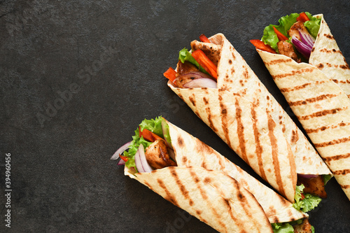 Mexican tortilla grilled wrap with chicken breast and vegetables on concrete background