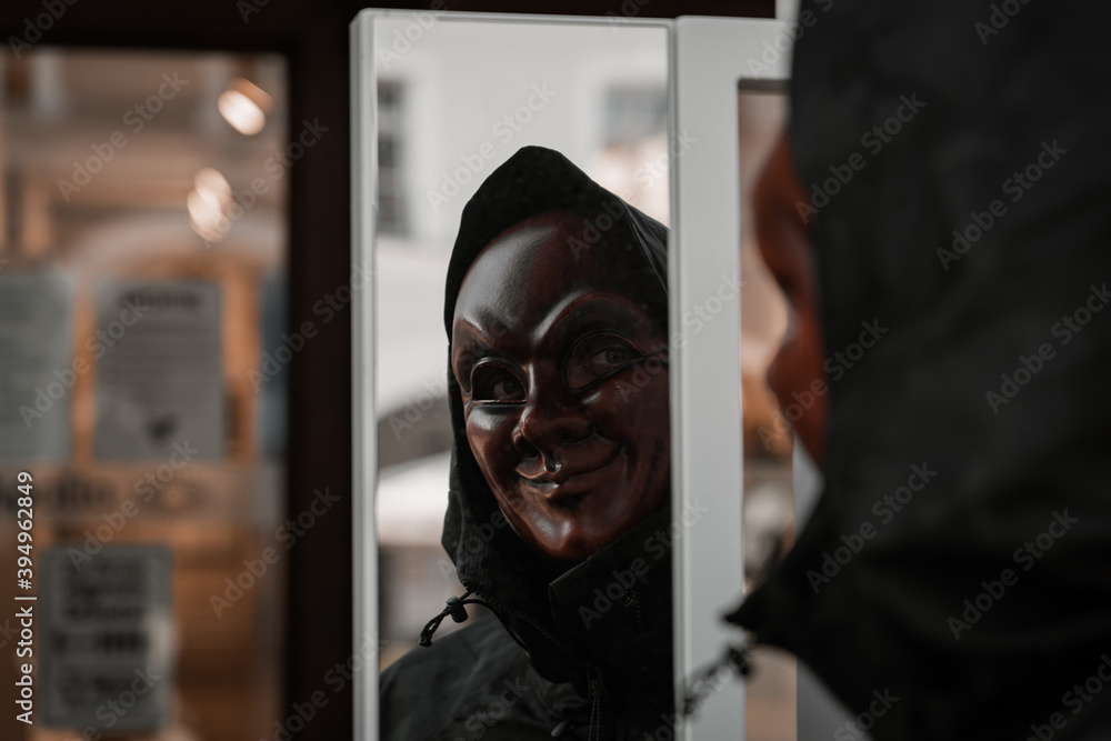 Reflection of a person in funny scary strange red mask with black jacket. Corona protective gear covid-19 style lifestyle rule of thirds creative art scary fear joke.