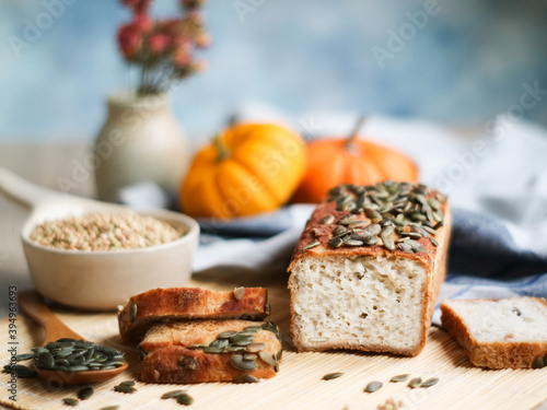 A healthy flour-less and multi grains  bread with a sliced pieces on a wooden plate. With pumpkin seeds and its fruit with a bowl of buckwheat grain. A healthy whole plant food and diet concept 