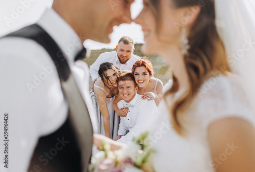 Newlyweds kiss on the background of friends