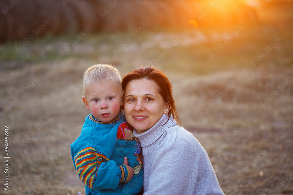 mother with little son in a stack of straw at sunset mother with little son in a stack of straw at sunset