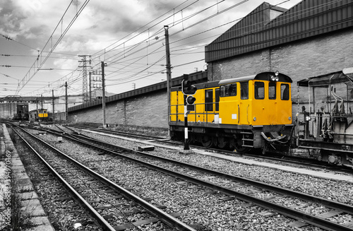 Locomotora de tren estacionado en blanco y negro con color amarillo de la locomotora resaltado