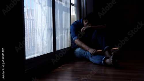 Depressed man Sit crouched beside window in the darkroom.