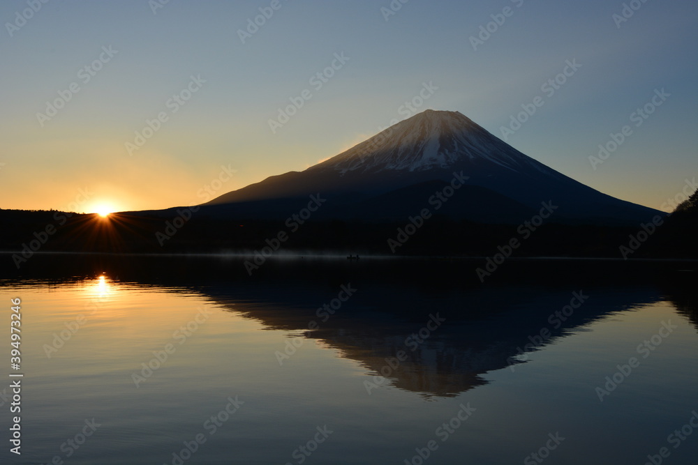 精進湖から朝日が差し込む富士山を望む