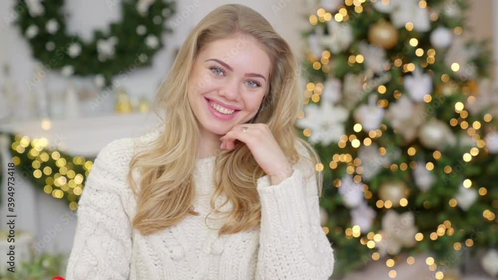 Fashionable smiling woman wearing knitwear cozy sweater in front of christmas tree Fashionable smiling woman wearing knitwear cozy sweater in front of christmas tree