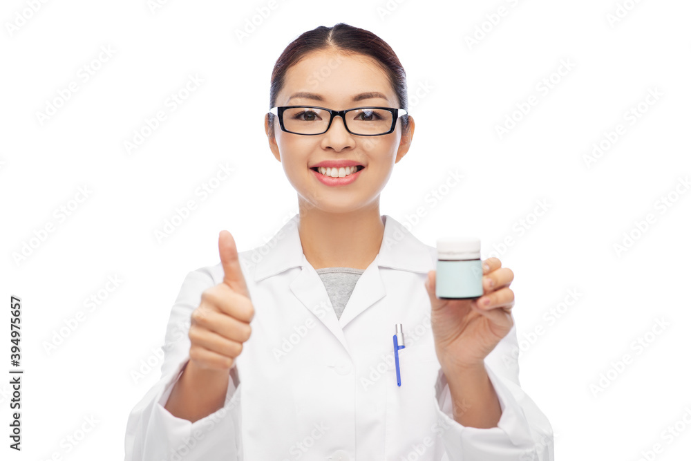 medicine, profession and healthcare concept - happy smiling asian female doctor, pharmacist or nurse holding jar of pills and showing thumbs up over white background medicine, profession and healthcare concept - happy smiling asian female doctor, pharmacist or nurse holding jar of pills and showing thumbs up over white background