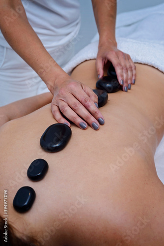 Masseuse putting hot stones on the back of pacient.Concept of beauty and wellness