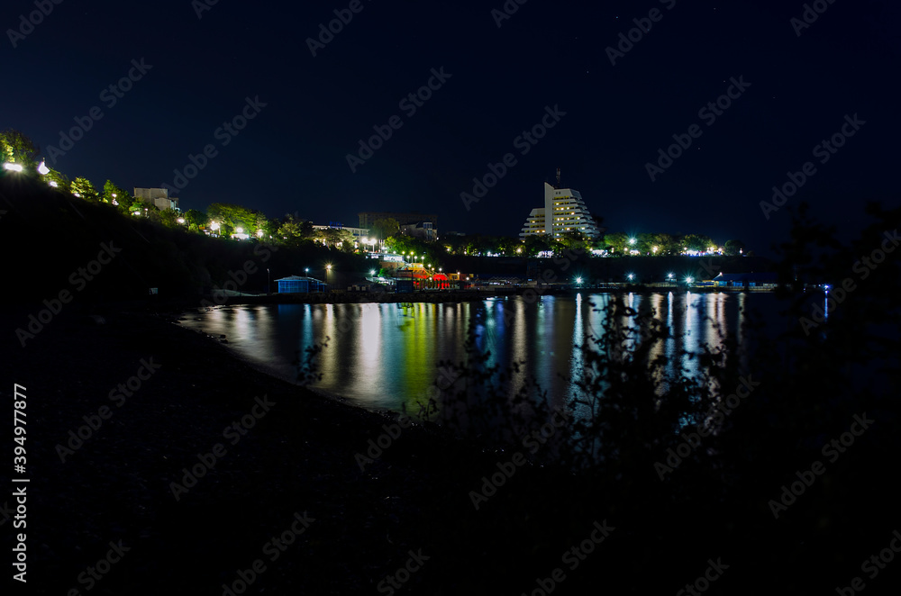 View from the sea to the night shore, the city Anapa in the lights from the lanterns