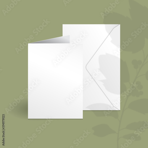 White vertical greeting card and envelope mockup template with holly berry branch with leaves overlay shadow.