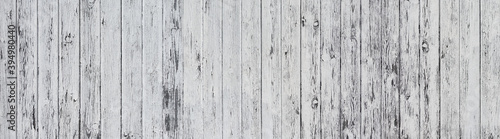 Panorama Holzwand aus vertikalen, hellgrau gestrichenen, stark verwitterten Brettern in Nahaufnahme