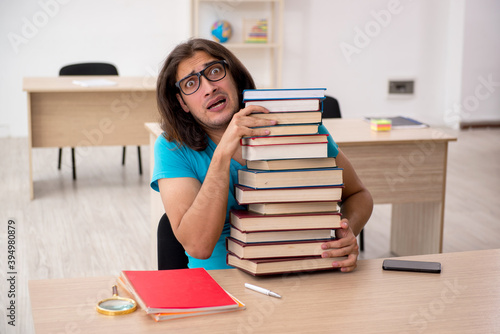 Young male student and a lot of books in the class