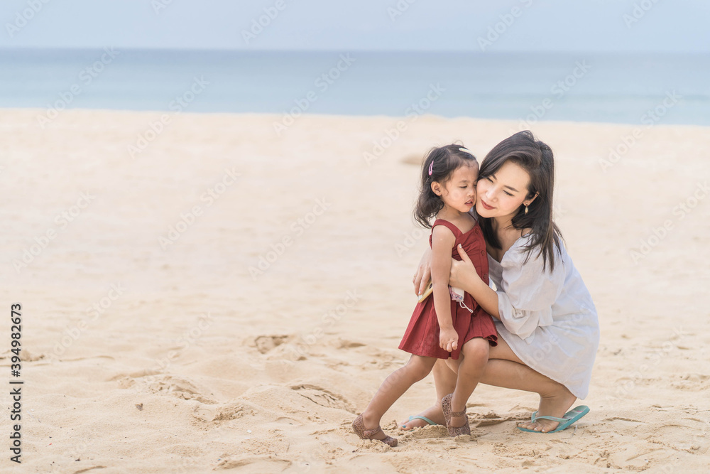 Beautiful Young mother and daughter sitting at the beach.