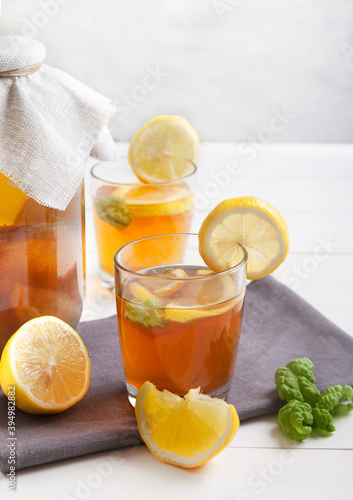 Two glasses and bank with kombucha and lemon slices on a white table. Copy spaec.