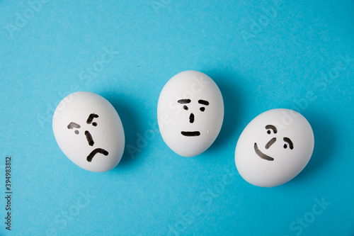 Eggs with faces and different emotions: anger, indifference and joy. Isolate on a blue background.