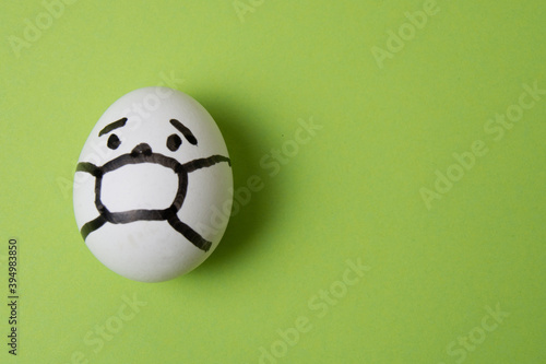 Egg with a person in a mask, on a green background. Quarantine concept covid 19