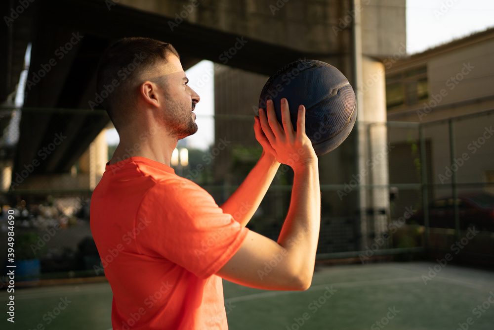 Caucasian young man playing basketball alone