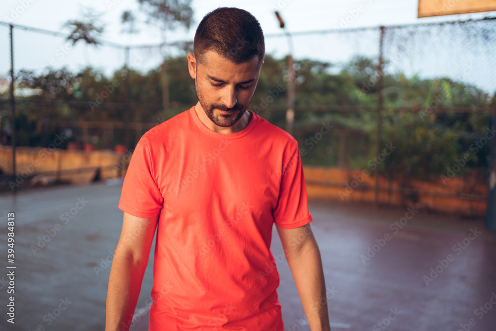 Caucasian young man playing basketball alone