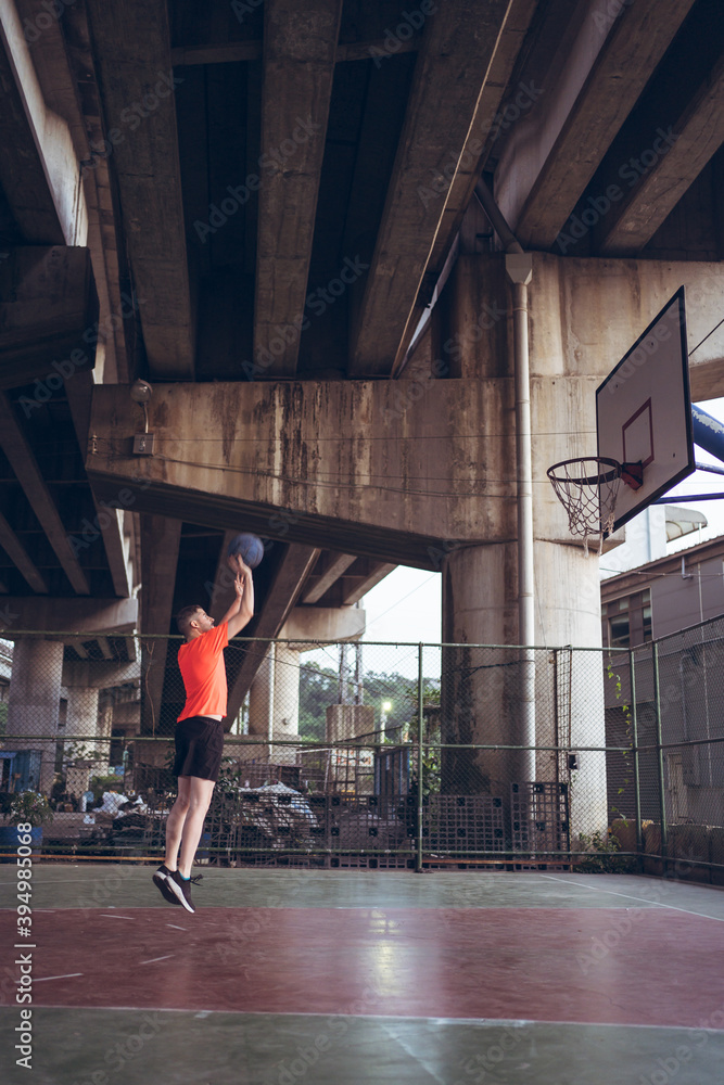 Caucasian young man playing basketball alone