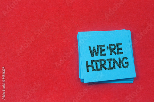 note paper written we're hiring over red background