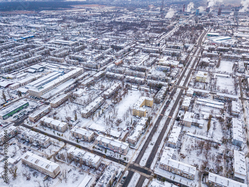 Top view from drone of city roads and houses covered with snow.