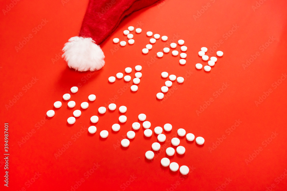 Stay home lettering from round white pills on a red background. Santa hat. High quality photo Stay home lettering from round white pills on a red background. Santa hat. High quality photo