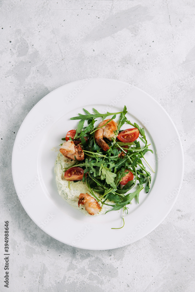 Arugula, shrimp and cherry tomato salad on a white plate Arugula, shrimp and cherry tomato salad on a white plate