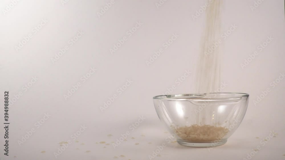 Pour long rice into a cup on a white background 4k sideways Pour long rice into a cup on a white background 4k sideways