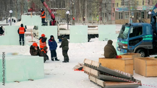 Workers build an ice town from ice blocks for the Christmas holidays