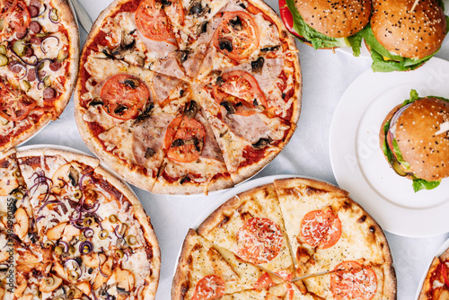 Assorted assorted pizzas and burgers on the table for tasting or working out the menu, top view