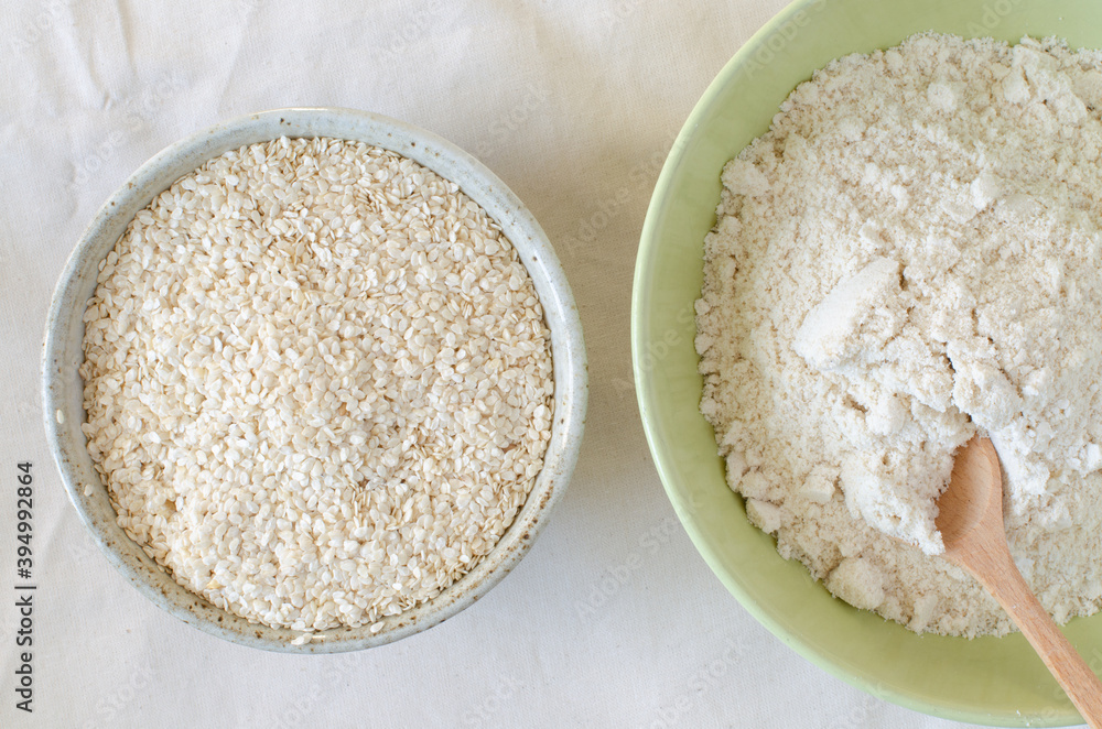 Squeezed white sesame and sesame flour in bowls on linen background. Benne oilcake. Top view. Squeezed white sesame and sesame flour in bowls on linen background. Benne oilcake. Top view.