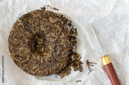 Chinese pressed raw puer tea. Sheng puer and tea knife on white paper. Top view photo