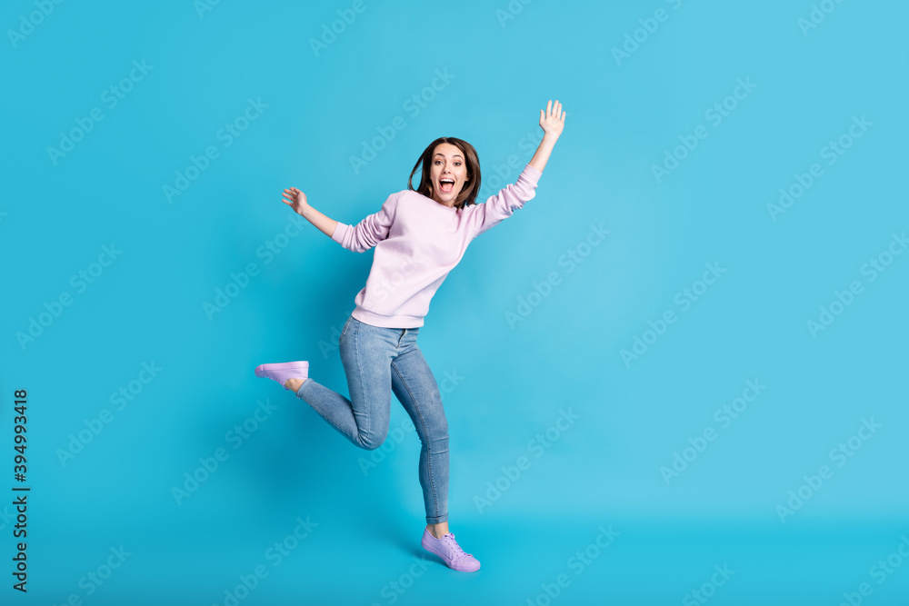 Full length photo of crazy funny teenager girl enjoy carefree rest relax holiday raise hands wear good look clothes isolated over blue color background