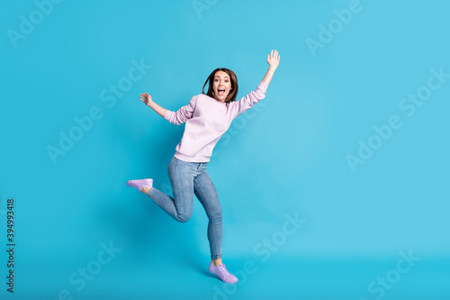 Full length photo of crazy funny teenager girl enjoy carefree rest relax holiday raise hands wear good look clothes isolated over blue color background