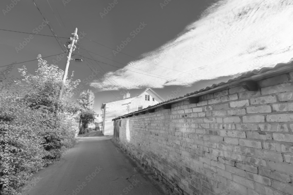Narrow street with stone fence and houses in countryside
