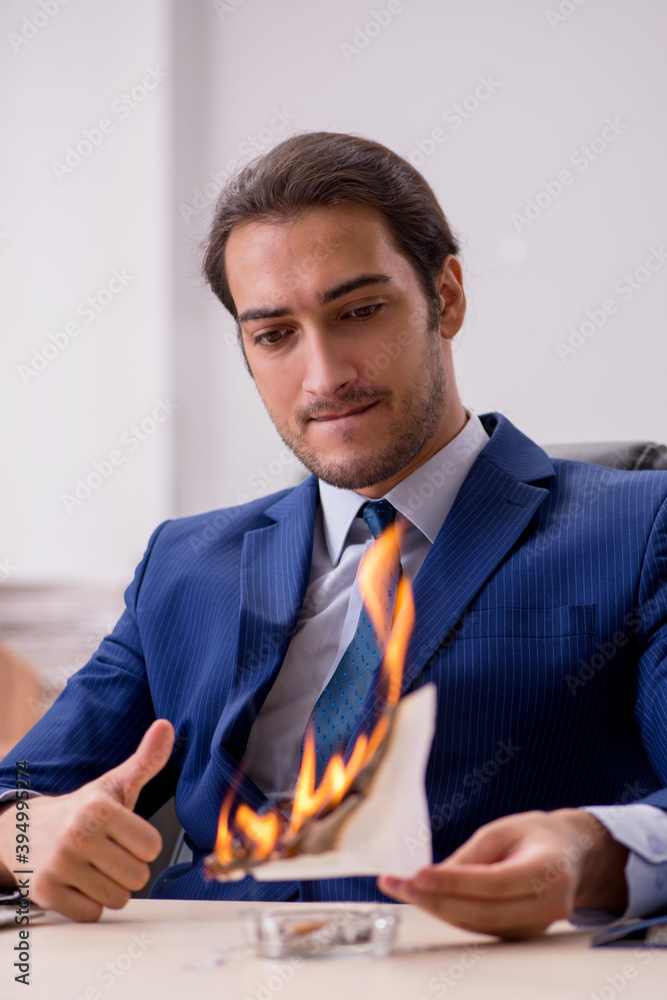 Young male employee burning papers in the office Young male employee burning papers in the office