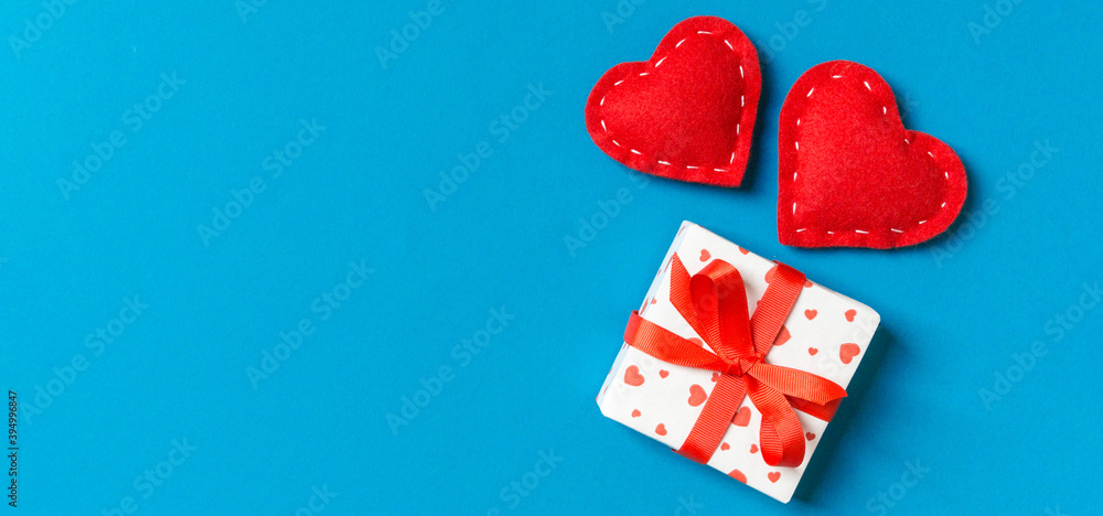 Fototapeta premium Top view of gift boxes and red textile hearts on colorful background. St Valentine's day concept with copy space