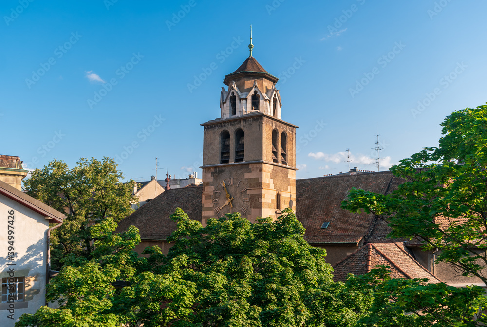 Geneva, Switzerland. View of the clock tower of Temple of the Madeleine against the background of roofs and trees.