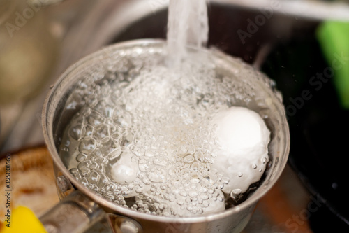 Cooling boiled eggs under running cold water.