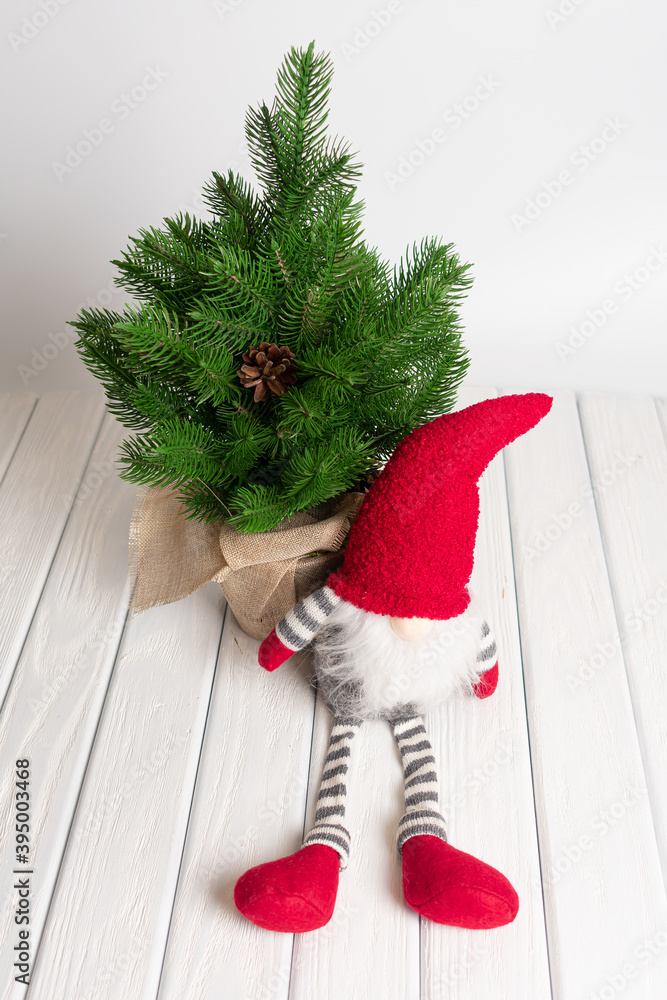 Obraz premium Christmas composition with gnome, gifts and festive decorations on a white background. New Year greeting card. Christmas gnome toy