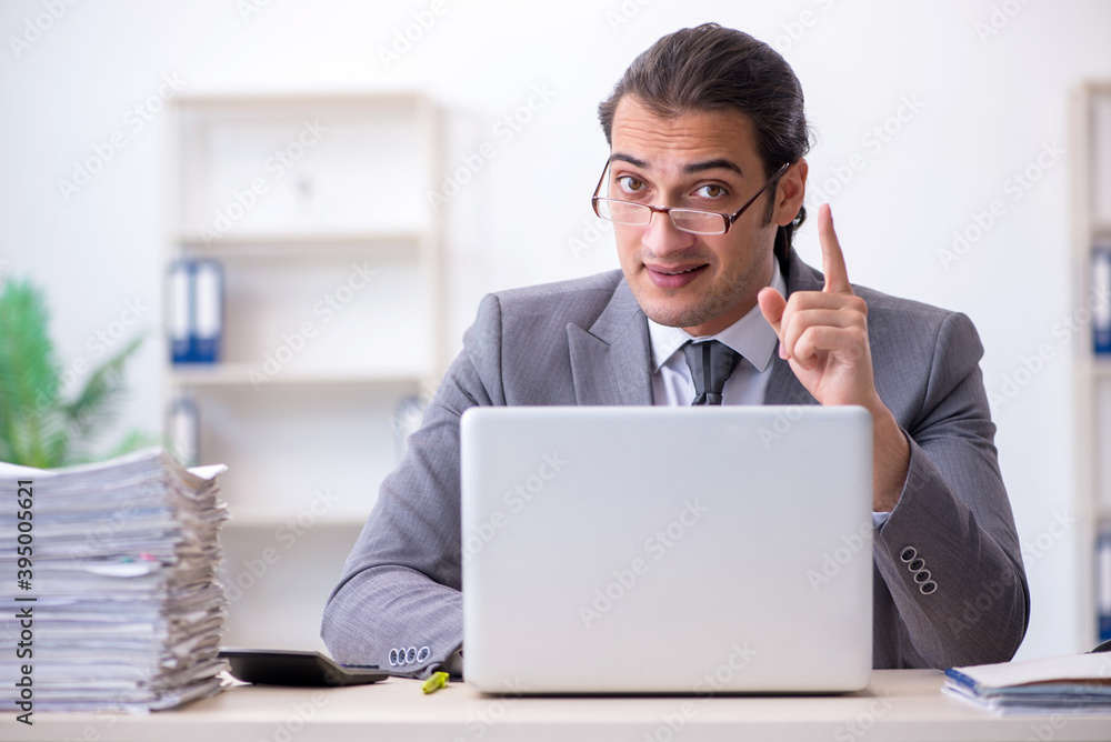 Young male employee unhappy with excessive work in the office Young male employee unhappy with excessive work in the office
