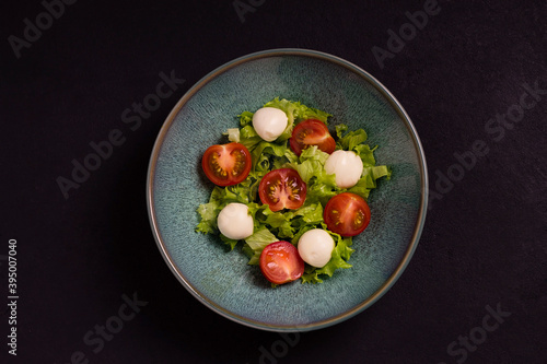 Italian caprese salad with mozzarella cheese, tomatoes and basil, in a plate. Top view