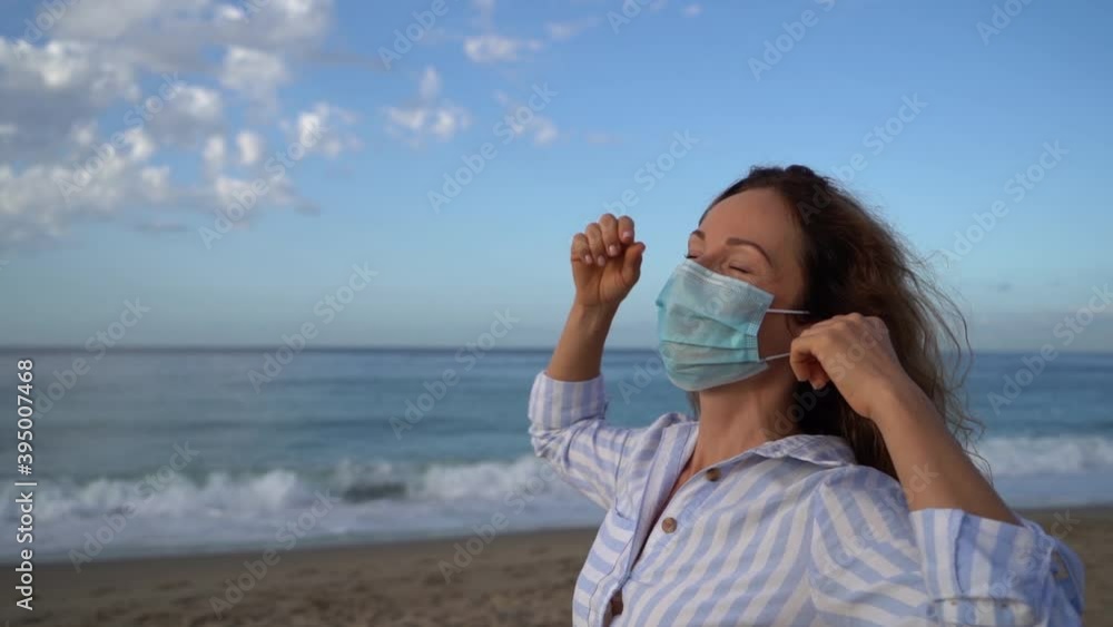 Happy woman wearing medical mask outdoor against blue sky background Happy woman wearing medical mask outdoor against blue sky background