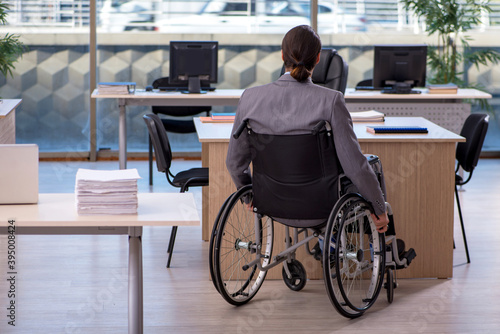 Young male employee in wheel-chair working in the office