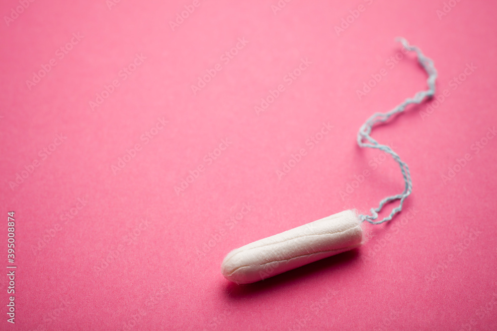 White tampon with light blue string on a colorful pink background. Shallow depth of field. White tampon with light blue string on a colorful pink background. Shallow depth of field.