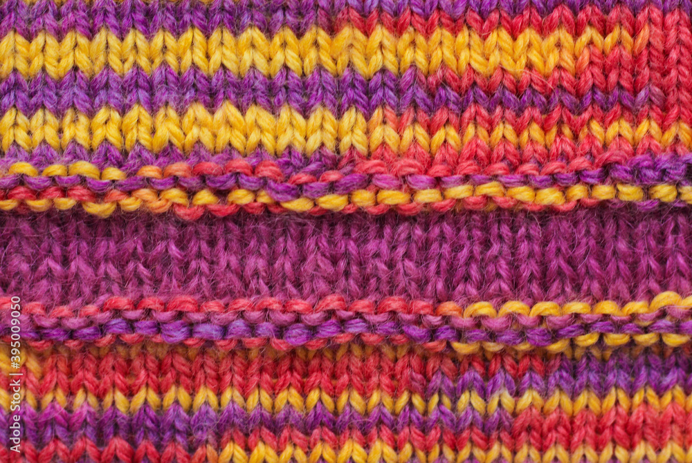 Knitted wool texture. Multicolored ornament - red, yellow, orange, purple.